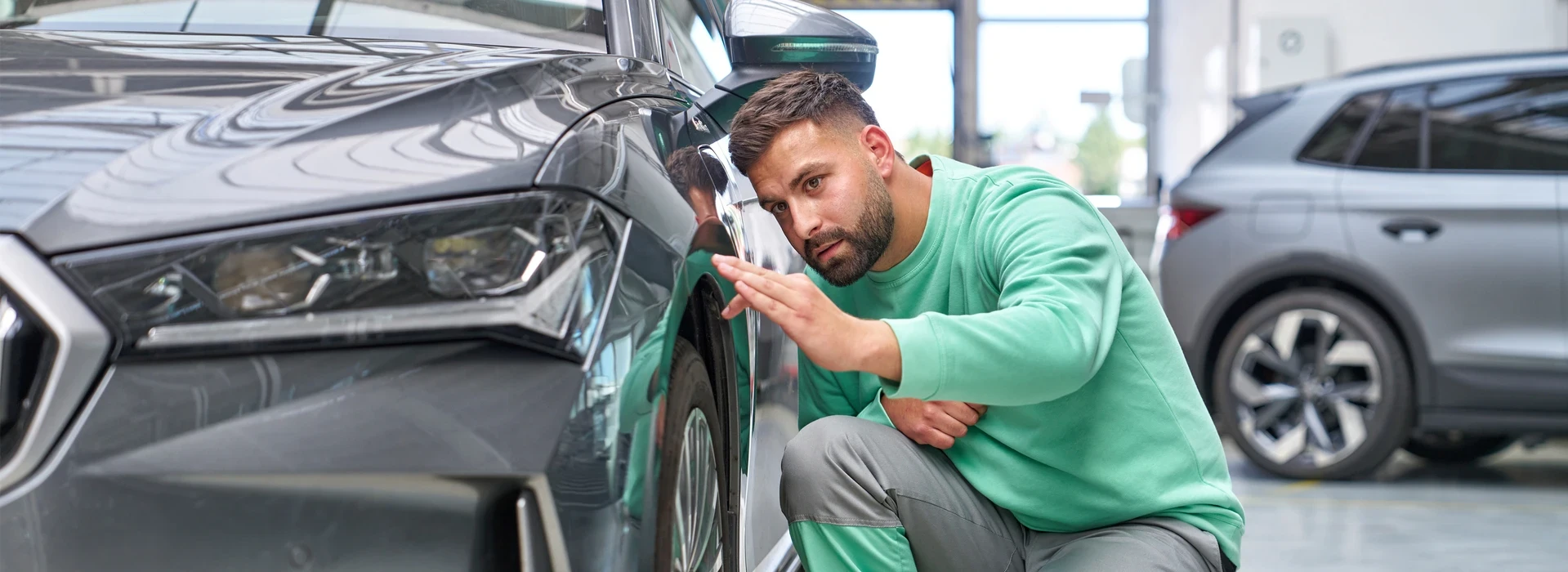 Servicemitarbeiter prüft Karosserie und Spaltmaß eines Škoda Fahrzeugs in der Werkstatt.