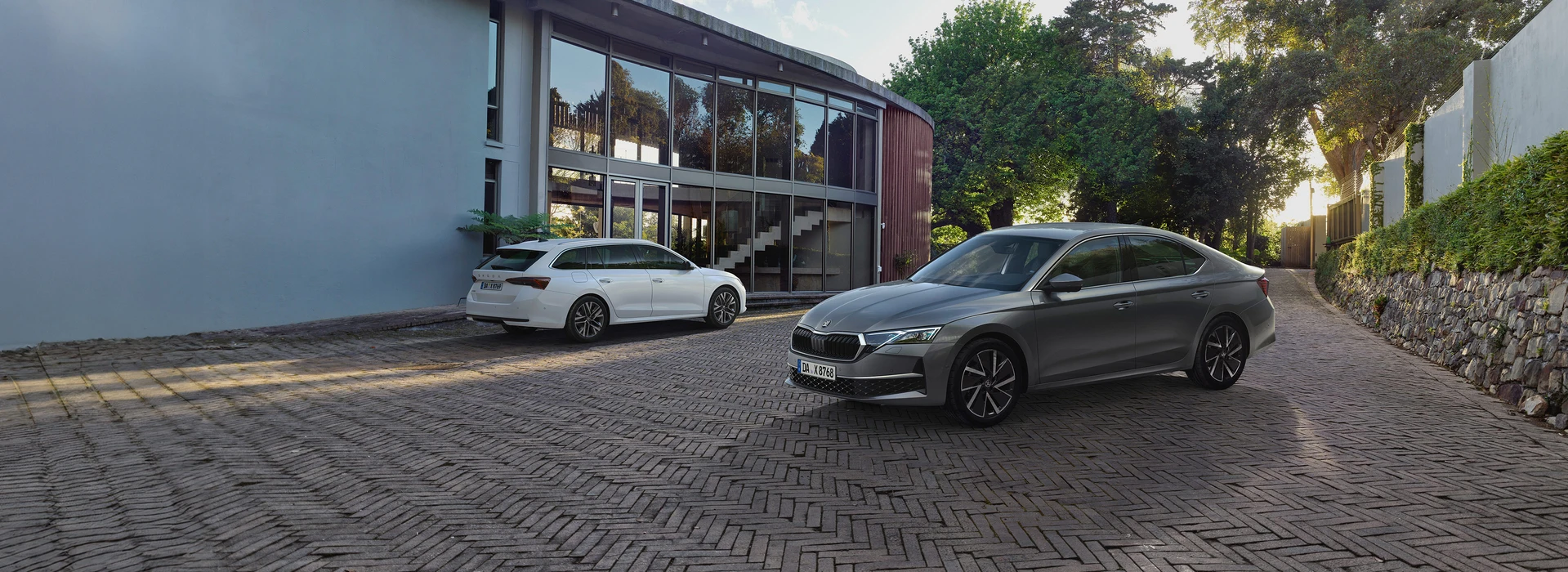 Die beiden Škoda Octavia Modelle (Limousine und Combi) in Einfahrt vor Einfamilienhaus mit Glasfront