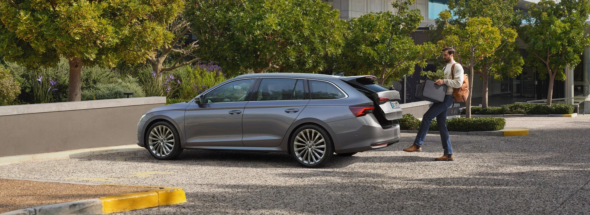 Mann öffnet den Gepäckraum des Škoda Octavia Combi per Fußsensor am Parkplatz.