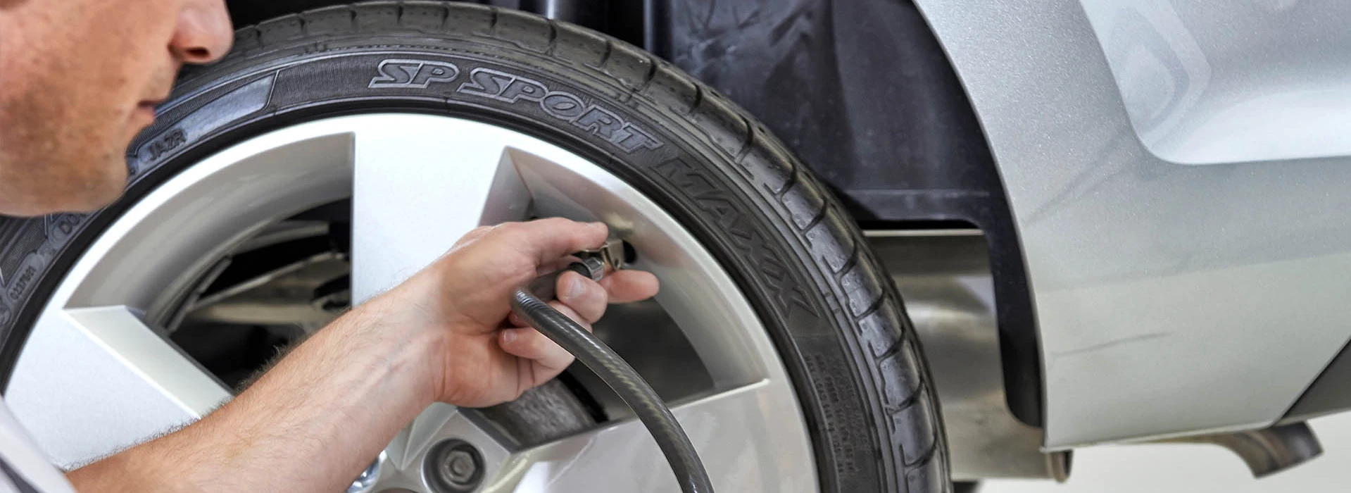 Service-Mitarbeiter prüft Reifendruck an einem Škoda-Fahrzeug mit analogem Manometer.