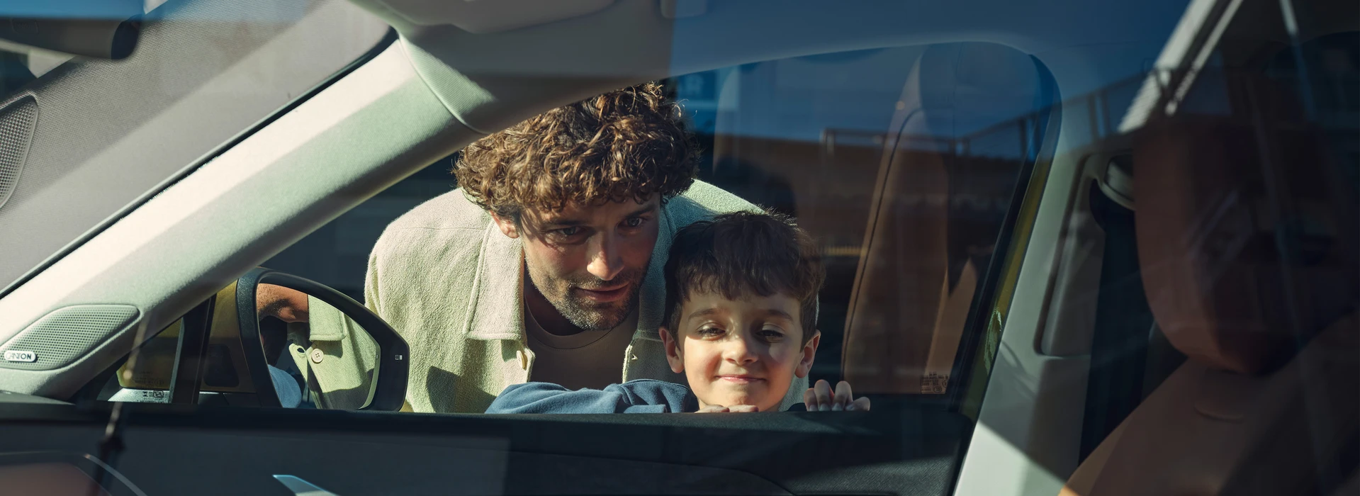 Vater und Sohn schauen durch das Fenster in ein Škoda Fahrzeug