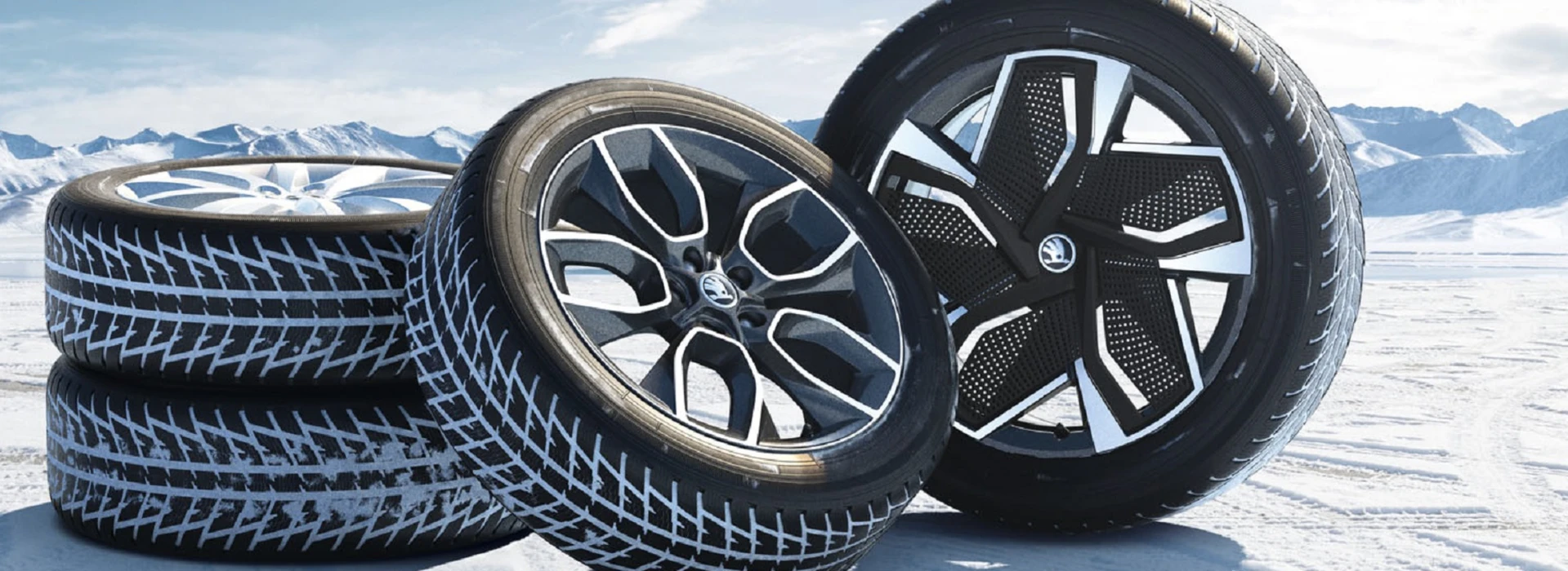 Vier Škoda-Felgen mit Winterreifen in einer verschneiten Berglandschaft