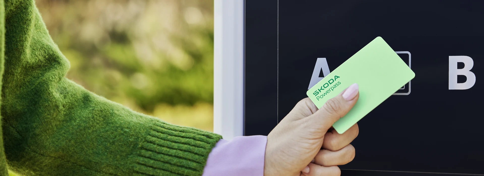 Nahaufnahme einer Škoda Powerpass-Karte, die an eine E-Ladesäule gehalten wird