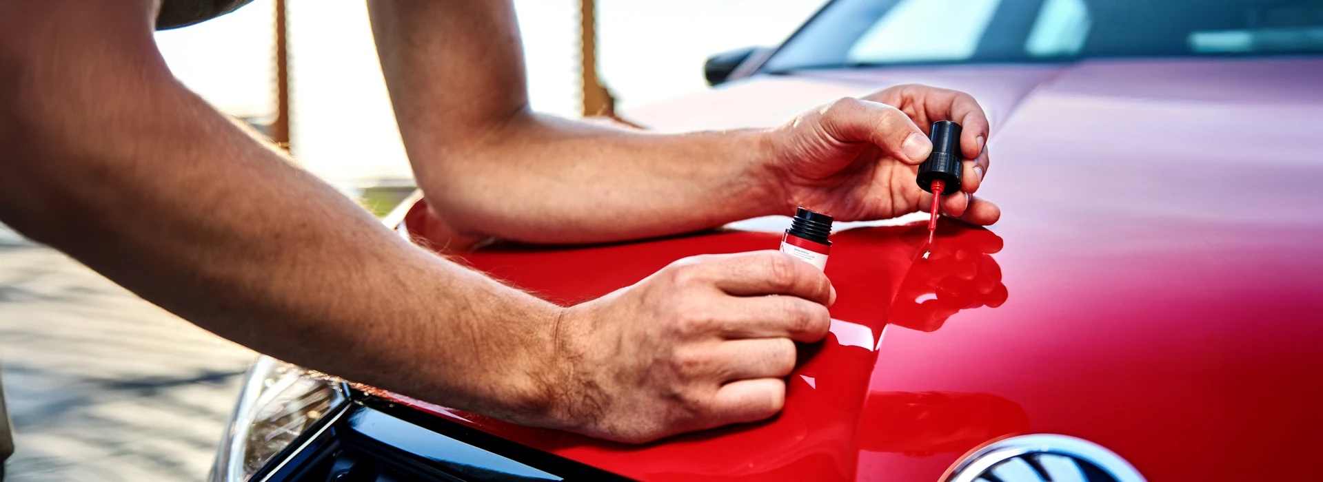 Closeup vom Ausbessern eines kleines Lackschadens auf Motorhaube eines Škoda Fahrzeugs