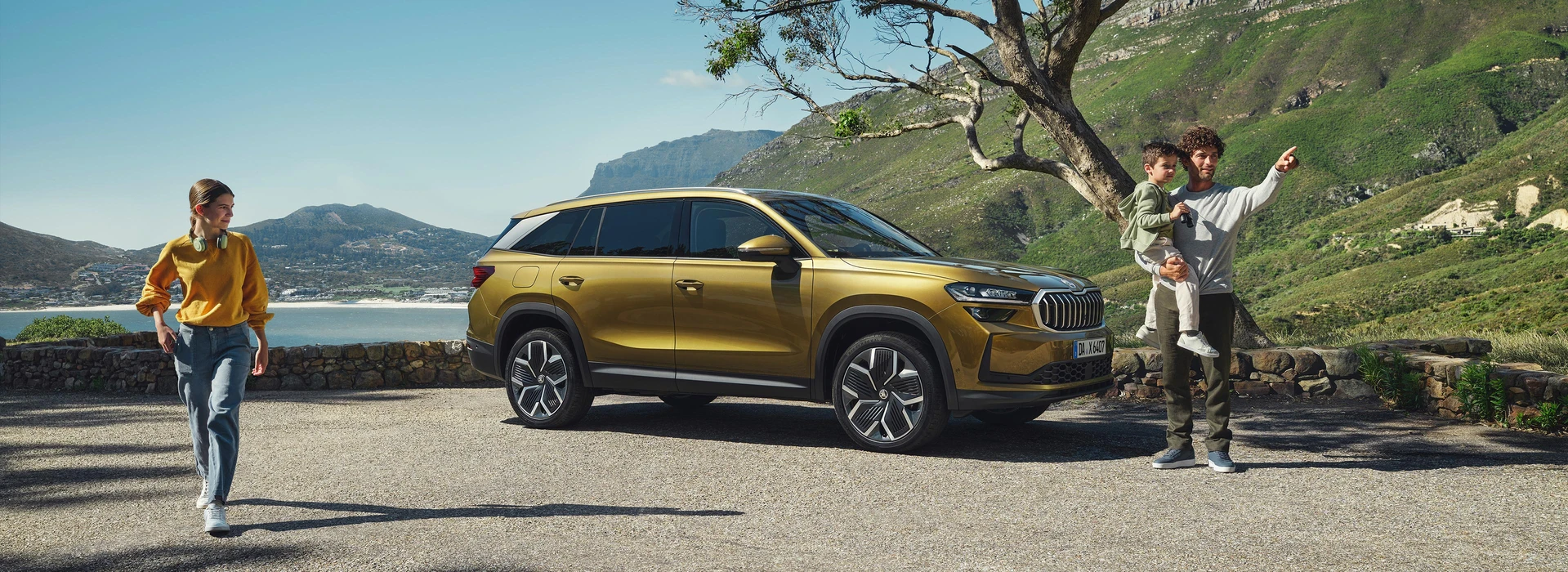 Familie mit Kindern vor goldenem Škoda SUV in Berglandschaft