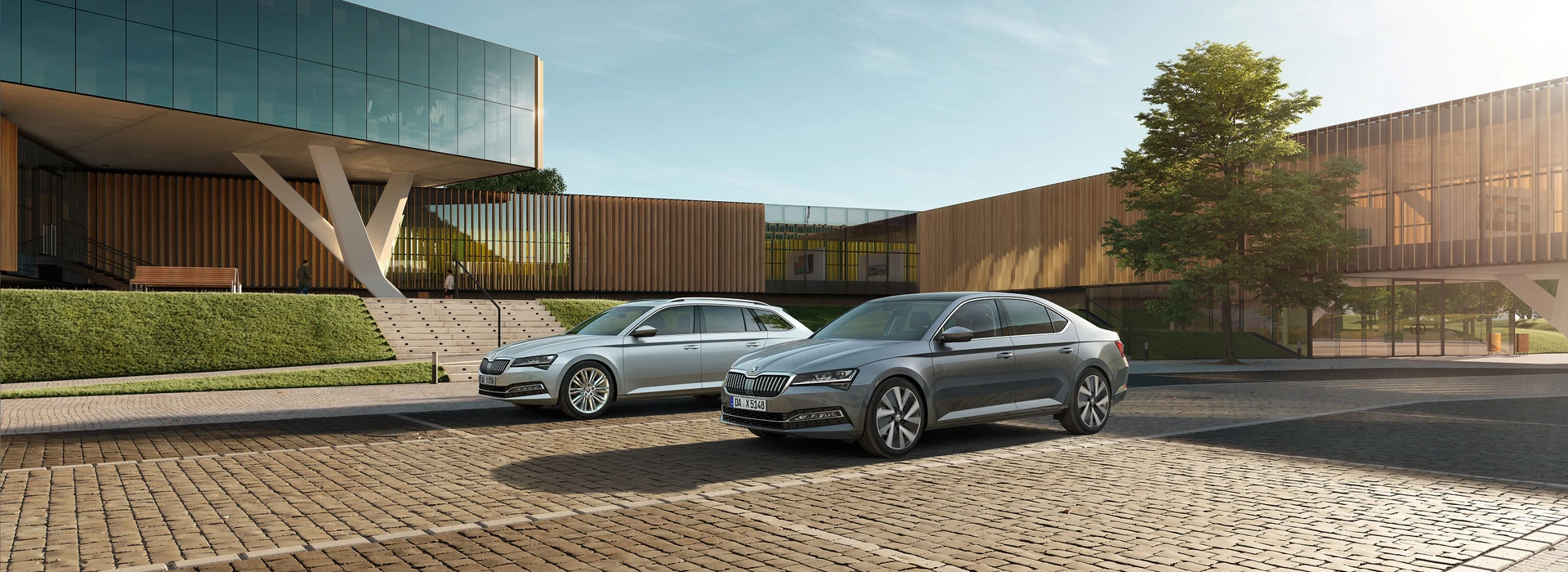 Zwei Škoda Superb Modelle vor moderner Firmenarchitektur mit Glas und Holzfassade.