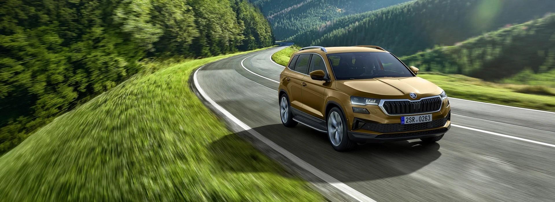 Škoda Karoq driving on the evening countryside road, ¾ rear angle, phoenix orange metallic color