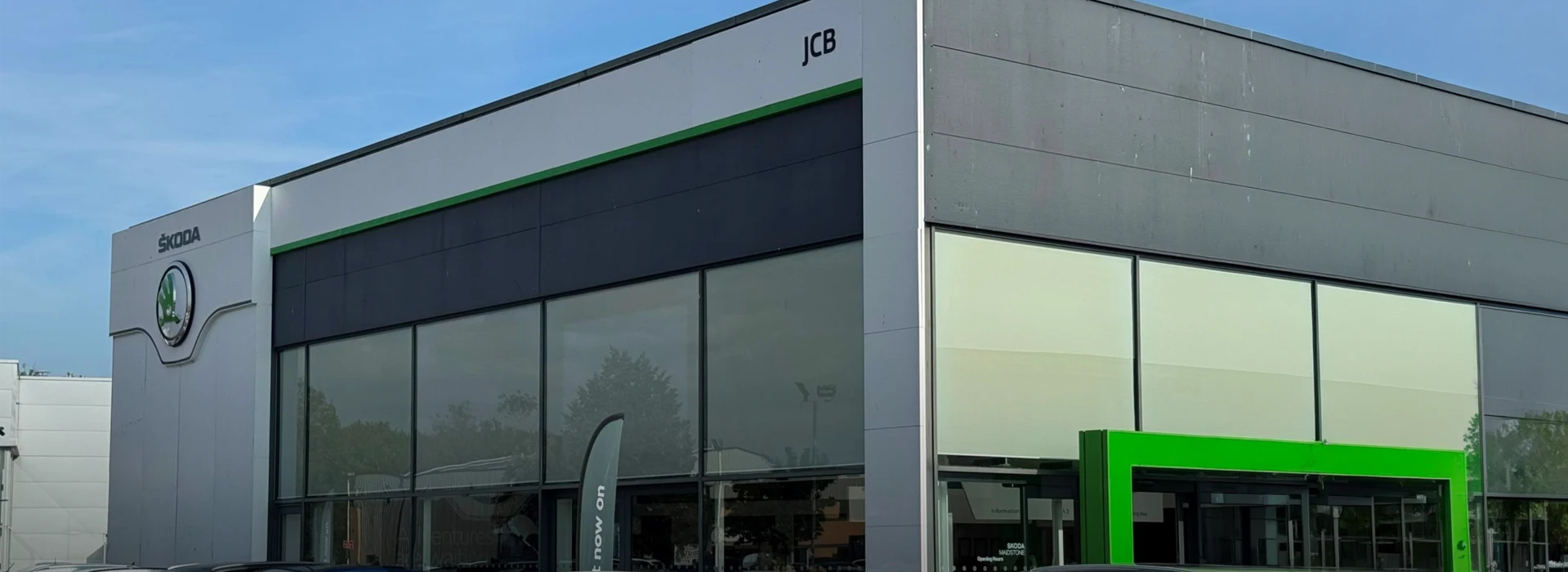 Exterior glass facade of the Škoda JCB car dealership showroom.