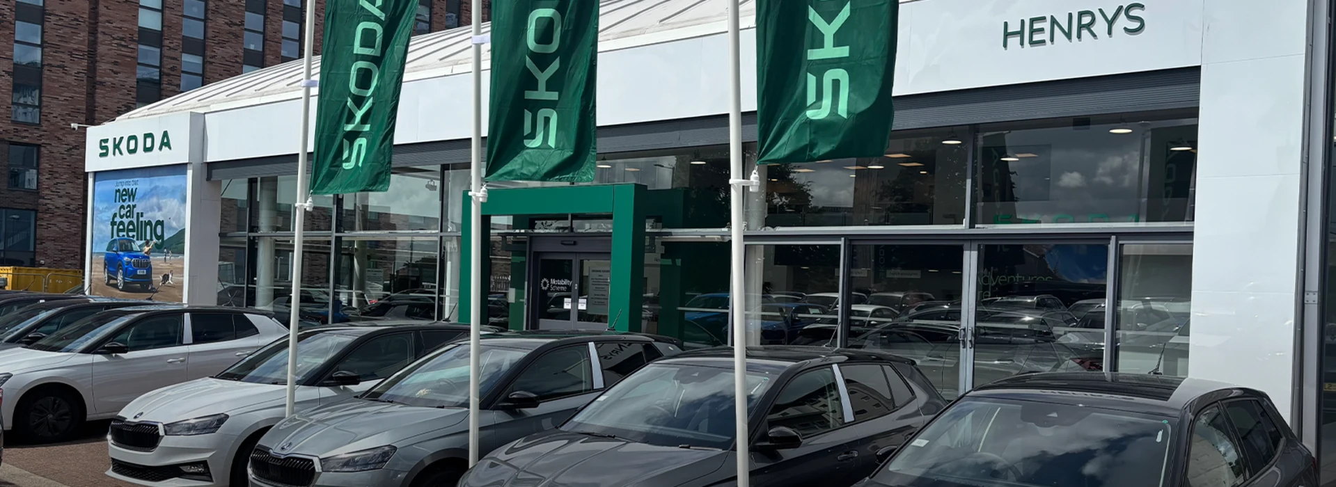 Front entrance and parked vehicles at the Škoda Henrys dealership building.