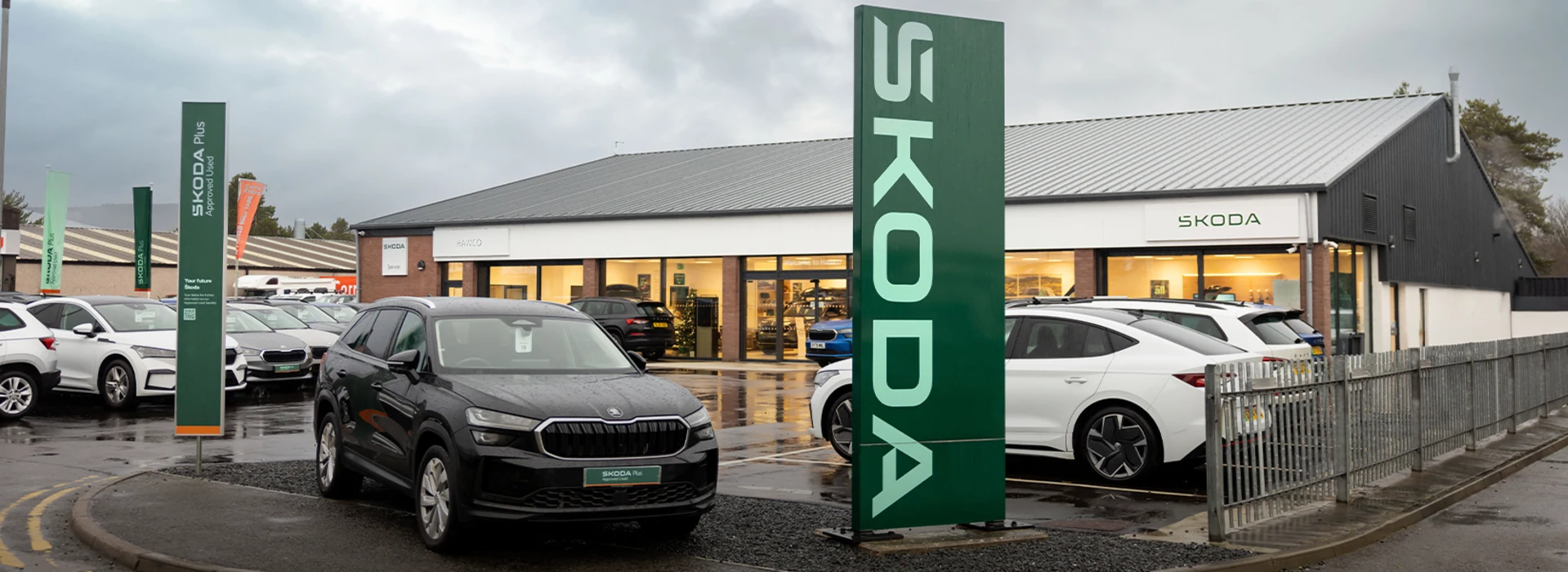 Exterior of the Škoda Ingram dealership showroom with cars displayed in the forecourt.