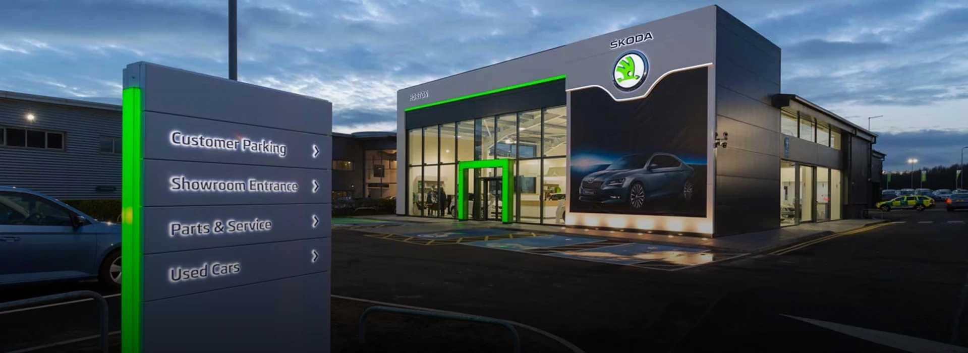 Škoda Horton Lincoln illuminated dealership exterior with entrance sign post at dusk.