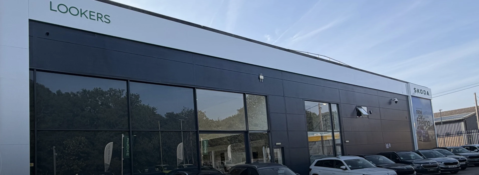 Modern glass exterior building of the Škoda Lookers car dealership showroom.