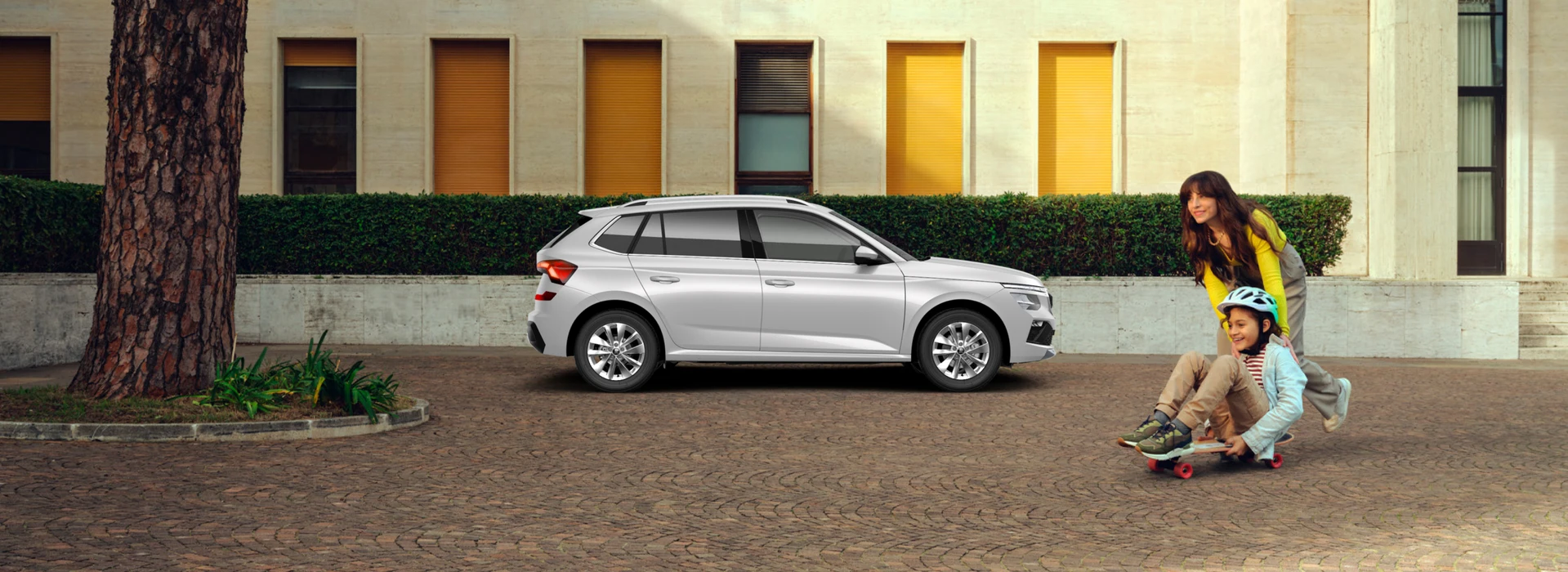 Madre e hijo jugando con un monopatín al lado de su coche Skoda Kamiq