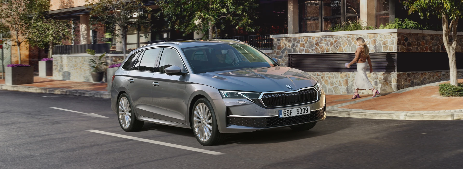 Vista di una ragazza che passeggia accamto Škoda Octavia Wagon.