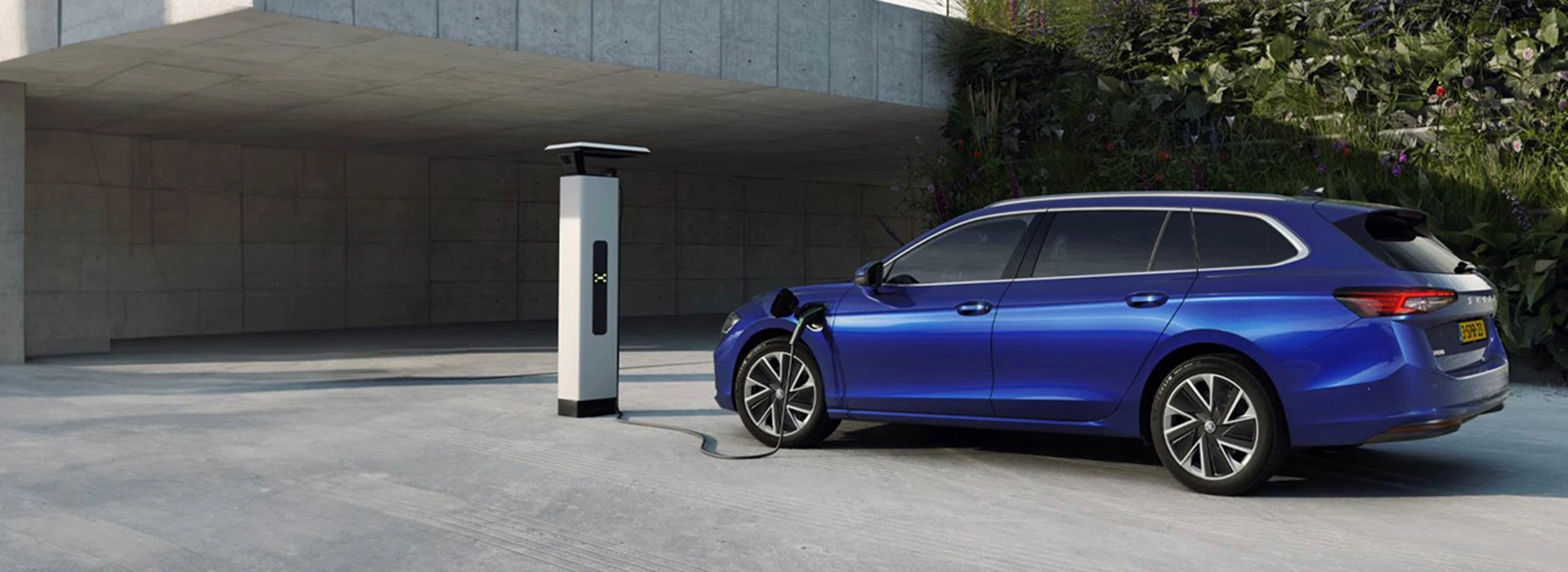 Een blauwe Skoda Octavia Combi wordt opgeladen bij een laadpaal