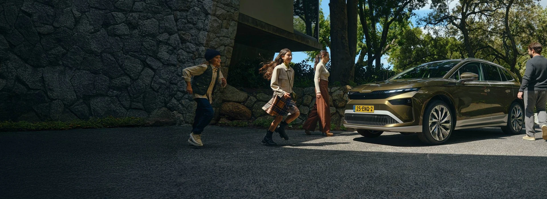 Een gezin loopt voor een Skoda Enyaq die voor een huis geparkeerd staat