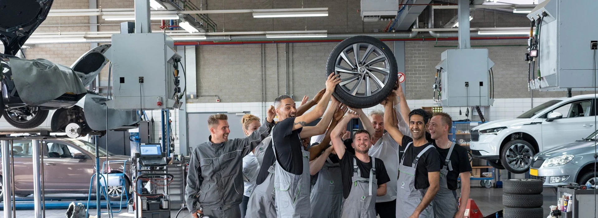 Een groep monteurs houdt een band in de lucht in de werkplaats