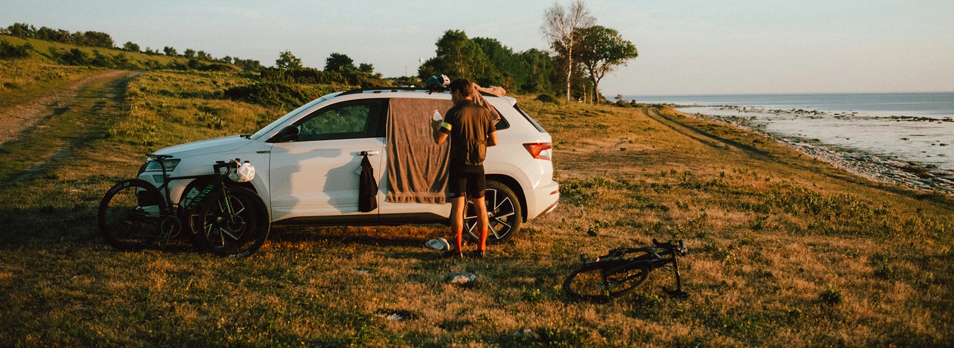 Skoda bil stående vid stranden med en person och cyklar.