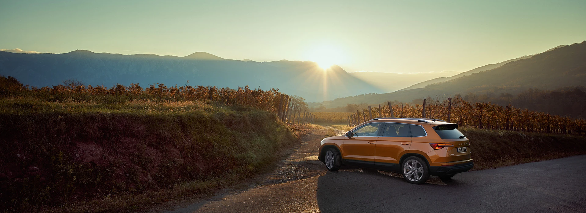 Karoq står på en väg på ett berg i solnedgången.