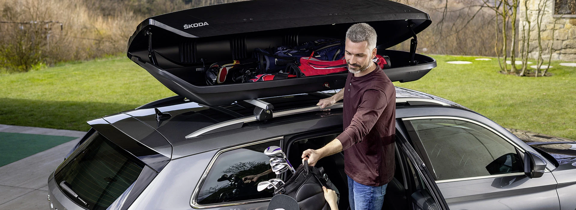 En man lastar golfklubbor ur takboxen på en Skoda