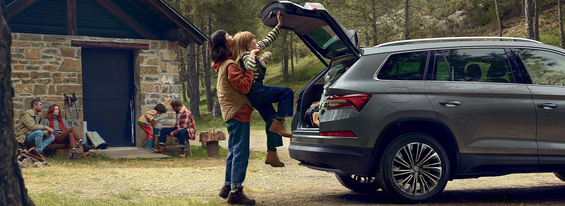 En mamma hjälper sin lilla dotter att stänga bakluckan på en Skoda.