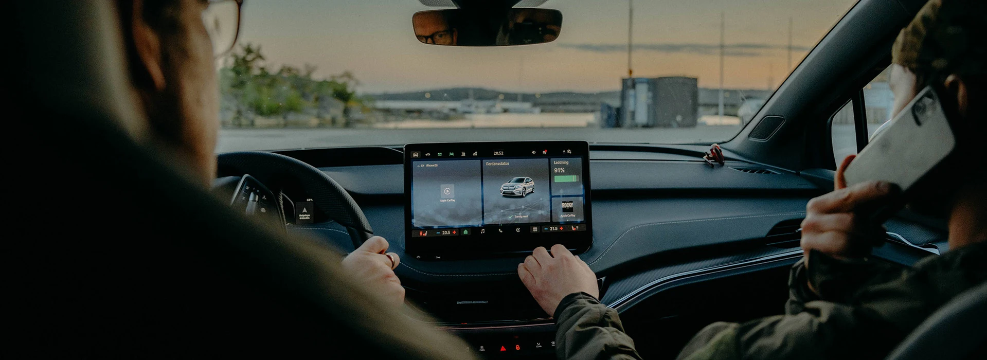 Personer sitter i bil och använder infotainment skärmen.